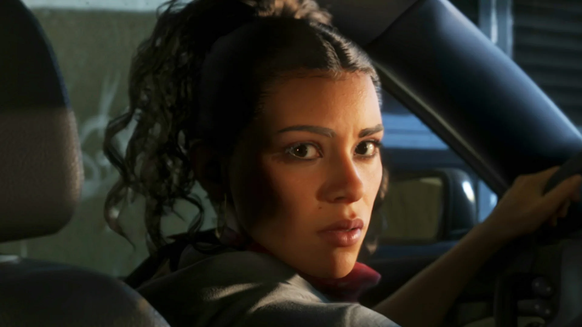 Lucia, protagonista di Grand Theft Auto VI, al volante di un'automobile mentre si gira indietro